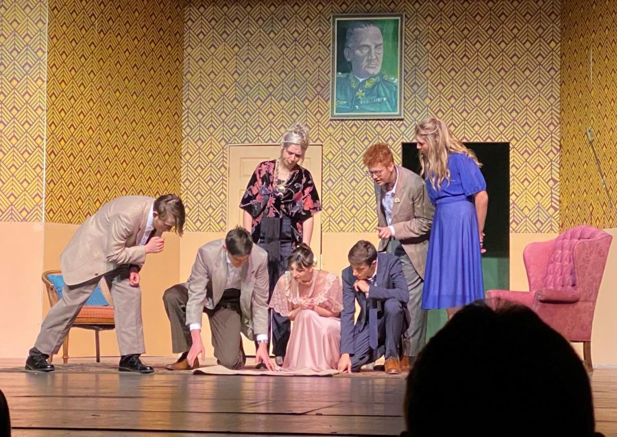 A group of characters from “The Musical Comedy Murders of 1940” gather around a set of blueprints of the estate during the second act of the play. 
