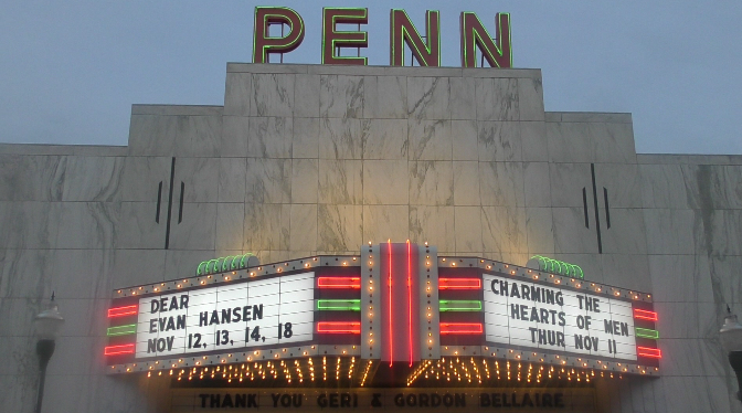 The Penn Theatres marquee brightly illuminating to attract patrons.