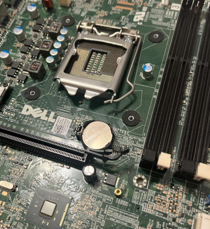 A Dell motherboard, lacking any other components, sits on the floor. December 6, 2022. 