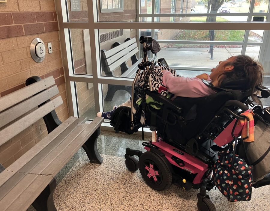 Maggie Hermann, Plymouth High School alumnus of 2022 gets as close as she can to the handicap door push button, which is blocked by a bench at the front entrace of Plymouth High School. October 20, 2022. 