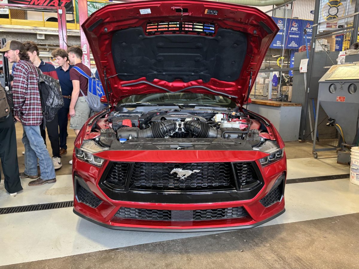 Students take a look under the hood of the red Mustang GT donated by Ford through Blackwell dealership. April 30, 2024.