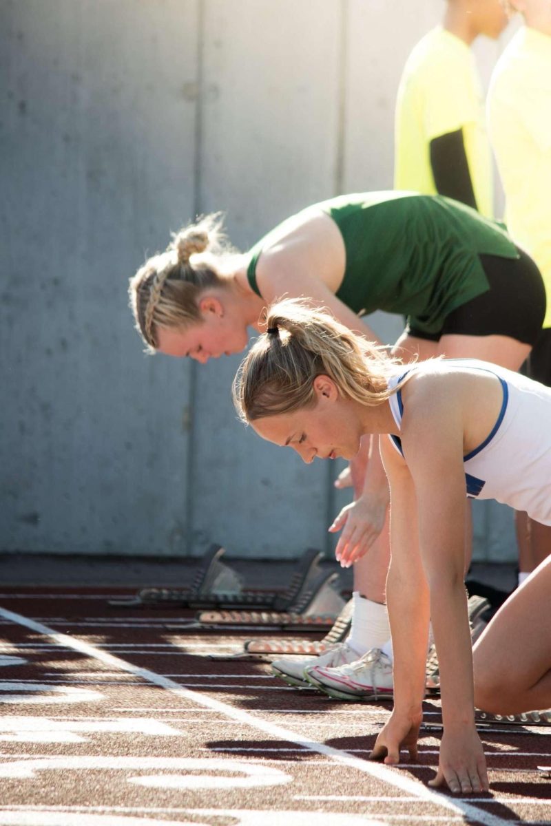 Julia Montgomery (right) readies herself to run the 100m hurdles during a meet against Novi. May 16, 2025.