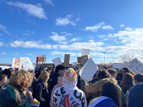 Hundreds of P-CEP students march in the bus loop, holding signs that display their opinions about immigration enforcement. In the middle, Ioannis Liabotis wears a hand-decorated hoodie with anti-ice messaging and a crossed-out crown. Feb. 4, 2026.